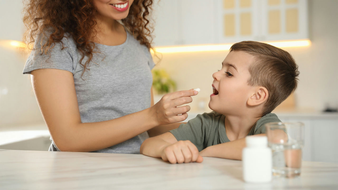Madre dando una pastilla a un niño
